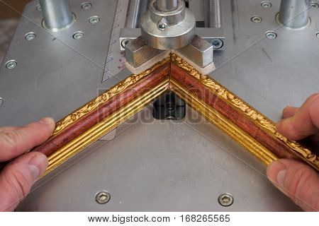 Craftsman working on frame in frameshop. Professional framer hand holding frame angle. Top view.
