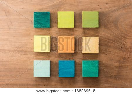 Index, menu or cover abstract back ground, consisting of nine hand painted colored wooden cubes on grungy wooden background with vintage taste. warm neutral colors. orange, gray, green, blue.