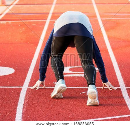 A sprinter training for the 100 mete dash on a high school track in the winter