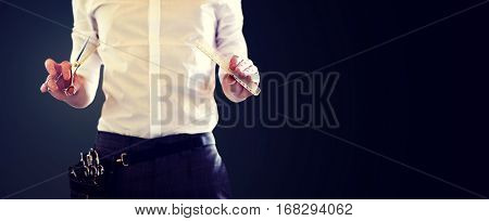 beauty and hair salon, hairstyle and people concept - close up of male stylist with scissors and comb over blank black background