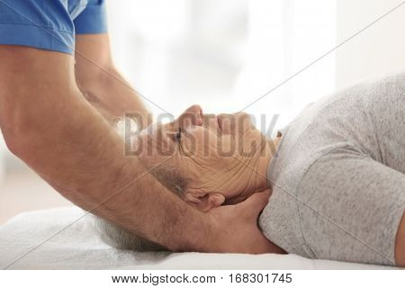 Physiotherapist working with elderly patient in clinic, closeup
