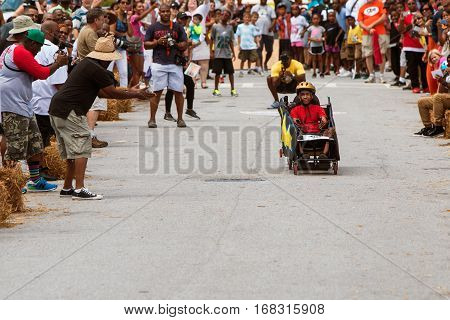 ATLANTA, GA - AUGUST 2016:  Spectators cheer on a kid racing in a soap box derby car at the Cool Dads Rock Soap Box Derby in the Old Fourth Ward in Atlanta GA on August 13 2016.
