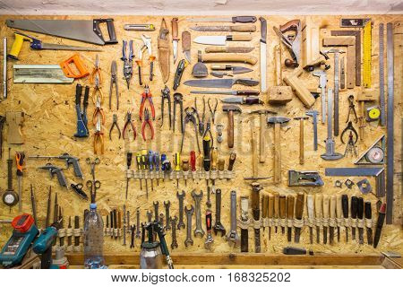 carpentry, woodwork and equipment concept - work tools hanging on wall at workshop