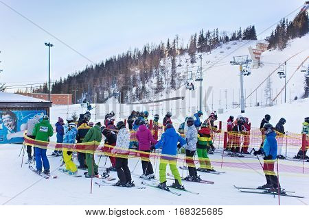 SLOVAKIA, STRBSKE PLESO - JANUARY 06, 2015: Skiers and other active people in Strbske Pleso. The village is a favorite ski tourist and health resort in the slovakian part of High Tatras mountains.