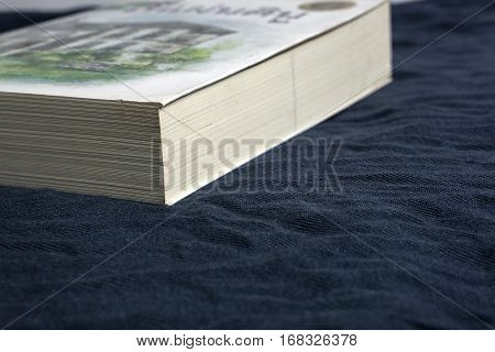 Thick book on the bed with dark blue background.