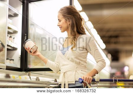 sale, food, shopping, consumerism and people concept - woman with ice cream at grocery store freezer