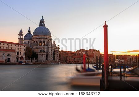 Grand canal in Venice during beautiful  sunset with parked gondolas in front in motion. Long exposure