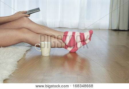 Lowsection of a woman in stripey socks holding remote control