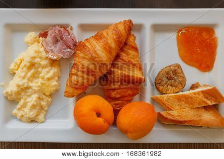 millet porridge, ham, croissants, peaches, bread, jam and figs at compartmental dish