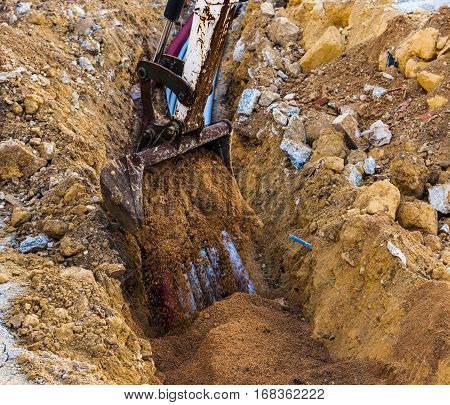 Excavator electrical conduits covered with sand with the assistance of a worker