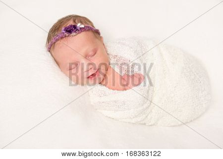 cute newborn baby in headband with flowers smiling asleep, closeup