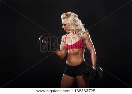 athletic young blonde curl girl doing a fitness workout with dumbbells on black background isolated