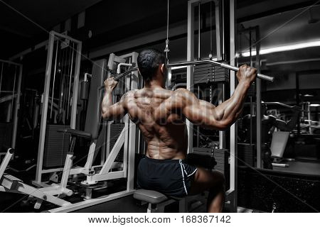 Athlete muscular bodybuilder training back on simulator in the gym