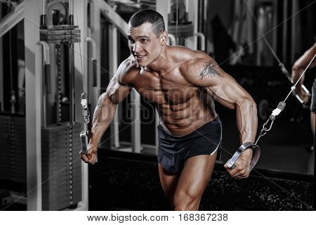 Athlete Muscular Bodybuilder Man In The Gym Training With Simulator
