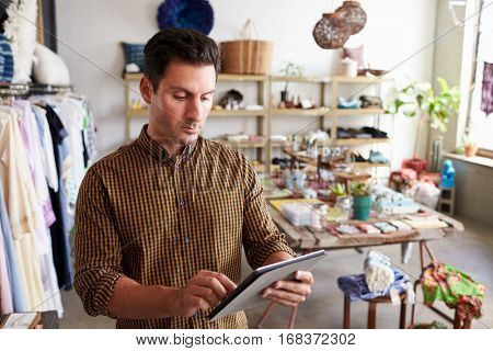Male manager using tablet computer in clothes shop