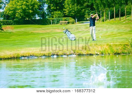 golf player hitting the ball into a lake