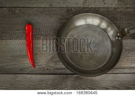 Red Hot Chili Peppers and pan on vintage wooden board. Top view with copy space.