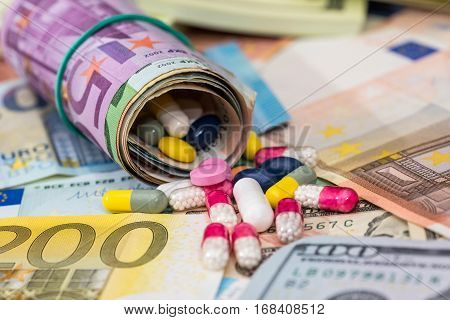 macro pills and tablets on euro and dollar banknotes for background.