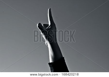 Hand open pointing finger showing number one towards cloudy sky on lowlight