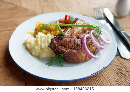 Fried pork ribs with sauerkraut and mashed potatoes on restaurant table