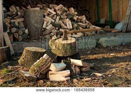 Axe in block on firewood just chopped background. Background of dry chopped firewood logs in a pile