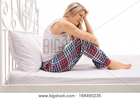 Depressed woman sitting on a bed and crying isolated on white background