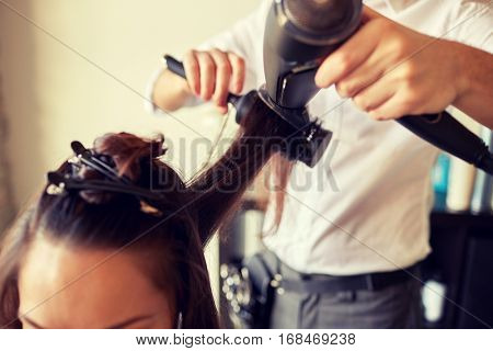 beauty, hairstyle, blow-dry and people concept - close up of young woman and hairdresser with fan and brush making hot styling at hair salon