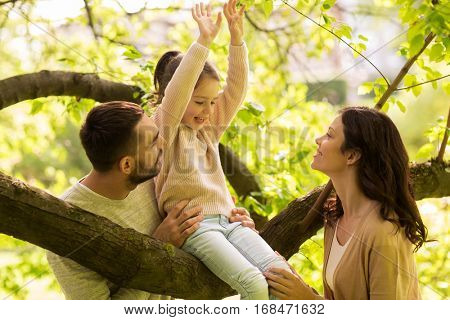 family, parenthood, adoption and people concept - happy mother, father and little girl in summer park having fun