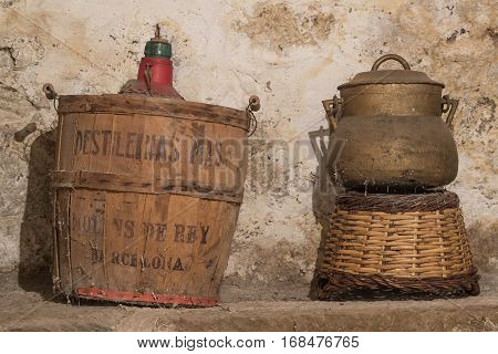 Antique carboy spanish demijohn and stewpot abandoned at the storage of an old house, with cobwebs and wall with humidity