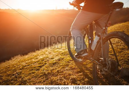 low angle view of cyclist standing with mountain bike at sunrise against bright sun and blue sky. sping season. Horisontal wide angle fisheye photo