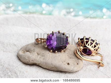Jewelry earrings with gems on sand beach background soft focus