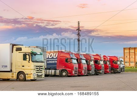 Narva Estonia - August 20 2016: Mercedes Volvo & Scania heavy trucks loaded with goods trailers parked in waiting area on Estonian-Russian state border crossing. International hard transportation and logistics. Transport infrastructure