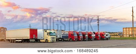 Narva Estonia - August 20 2016: Mercedes Volvo & Scania heavy trucks loaded with goods trailers parked in waiting area on Estonian-Russian state border crossing. International hard transportation and logistics. Transport infrastructure