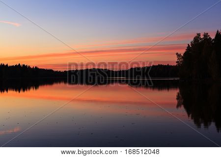 Serene view of calm lake and sunset clouds at twilight