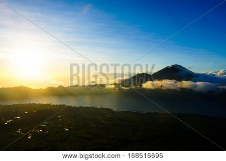 The sun rises and casts a golden haze over Bali's Lake Batur
