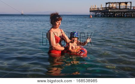 DIDIM TURKEY - JULY 9 2014. Mom teaches her son the boy to swim in the sea.