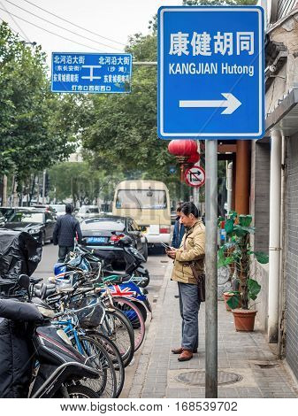 Beijing, China - Oct 30, 2016: Along Dengshikou West Street. A sign showing direction to Kangjian Hutong. Hutongs are narrow traditional streets or alleys commonly found in Old Beijing.