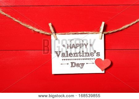 Valentines message card with small red heart hanging with clothespins