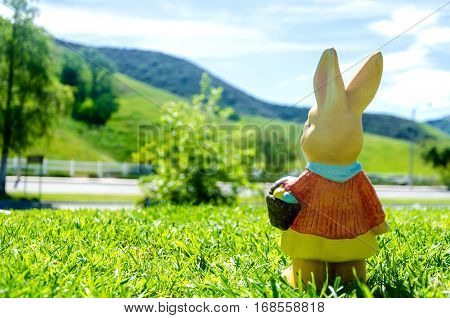 Easter bunny waith basket and color eggs in field - American landscape