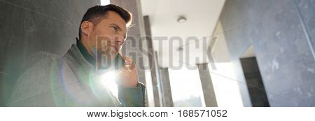 Businessman leaning on wall talking on phone