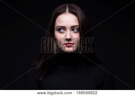 Portrait of looking right young woman on black background