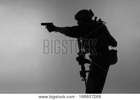 United states Marine Corps special operations command Marsoc raider with weapon aiming pistol. Silhouette of Marine Special Operator gray background