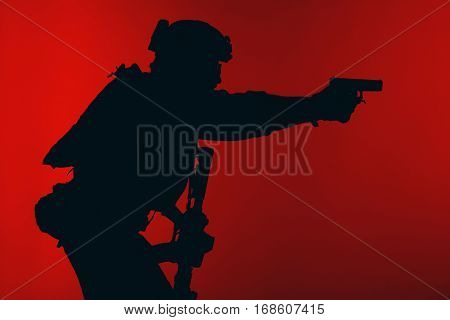 United states Marine Corps special operations command Marsoc raider with weapon aiming pistol. Silhouette of Marine Special Operator red background