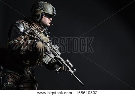 United states Marine Corps special operations command Marsoc raider with weapon. Studio shot of Marine Special Operator half-turning black background