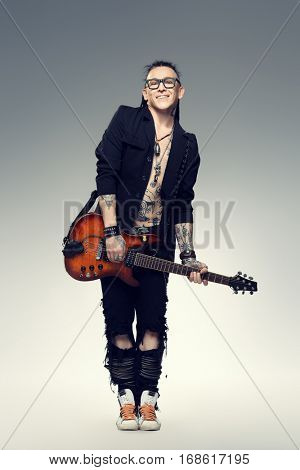 Excited rock musician is playing electrical guitar. Full length studio shot. Entertainment and musical concept. 