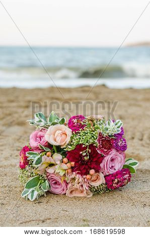 Colorful wedding bouquet from roses. Pink, red and green colors. Beach wedding.