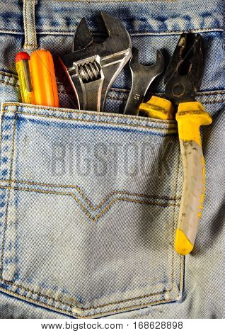 Different hand tools in a pocket of the blue jeans