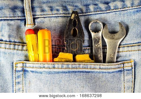 Different hand tools in a pocket of the blue jeans