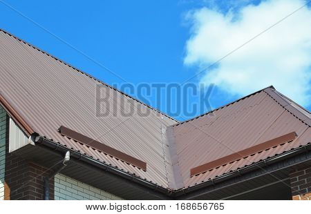 Closeup of problem areas for rain gutter roof waterproofing and roof protection from snow board (Snow guard) on new metal house roof construction