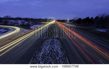 Multi-lane highway during rush hour winter commute light trails showing motion of cars